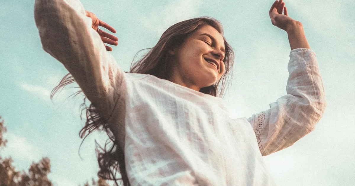 Mujer sonriente con los brazos abiertos al aire libre