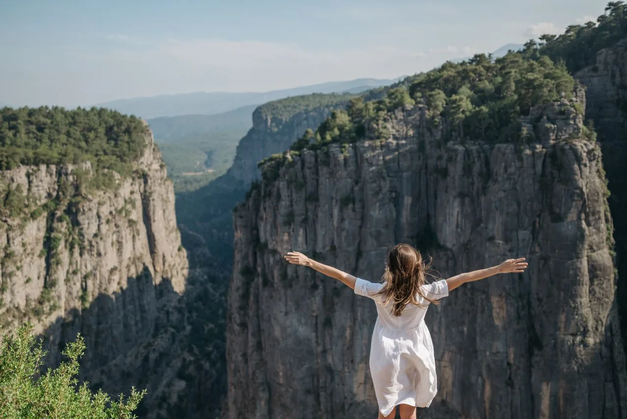 Mujer con los brazos abiertos disfrutando de la naturaleza